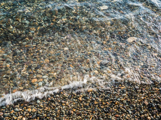 Obraz premium pebble beach and clear surf wave. sea coast