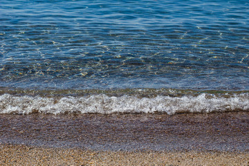 a wave running to a sandy beach