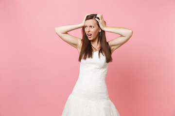 Portrait of concerned shocked bride woman in white wedding dress standing looking aside clinging to...