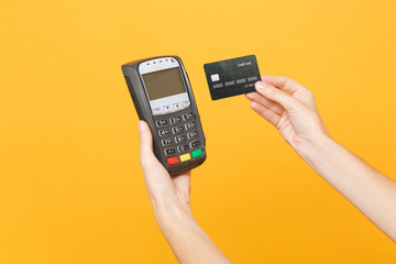 Close up cropped photo of female holding in hands wireless modern bank payment terminal to process and acquire credit card payments black card isolated on yellow background. Copy space for advertising