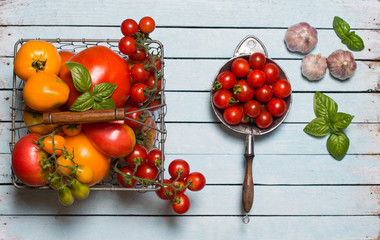 Variety of Colorful Organic Tomatoes in metal basket and vintage strainer on wooden background with...