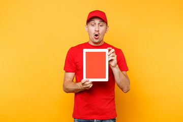 Delivery man isolated on yellow orange background. Professional male employee courier in red cap, t-shirt holding tablet computer with blank empty screen. Service concept. Copy space. Mockup template.