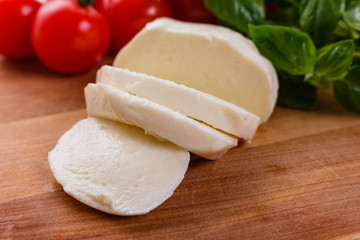 Mozzarella tomatoes and basil on a wooden rustic background