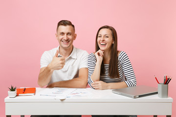 Two young smiling business woman man colleagues sit work at white desk with contemporary laptop isolated on pastel pink background. Achievement career concept. Copy space advertising, youth co working