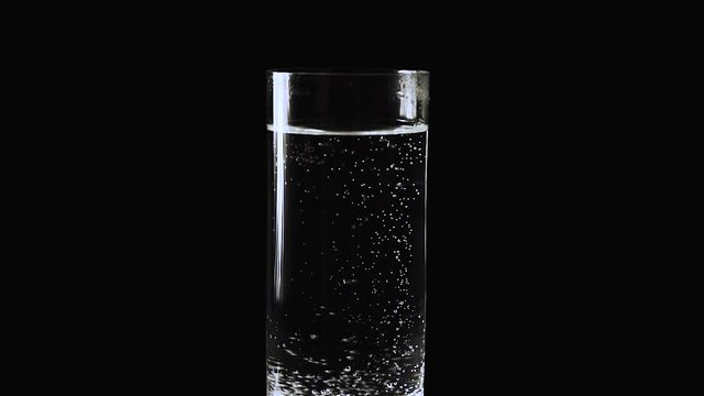 Water being poured into Glass against Black Background, Slow Motion