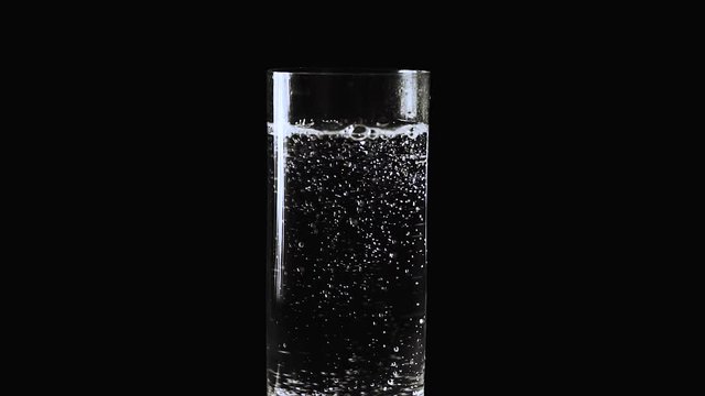 Slow mo. Bubbles from mineral water, soda in a glass on a black background