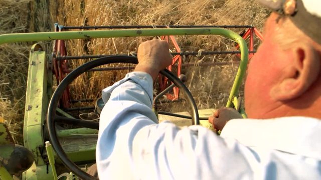 Senior man driving combine, close up. Harvesting crop. Agriculture work.