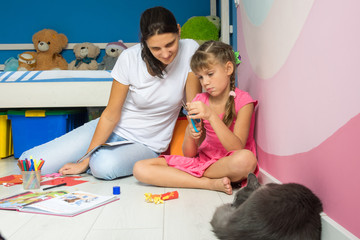 Obraz premium My daughter and mother are making figures from colored paper, a cat is sleeping nearby