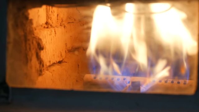Old working gas fireplace in which a flame of fire burns