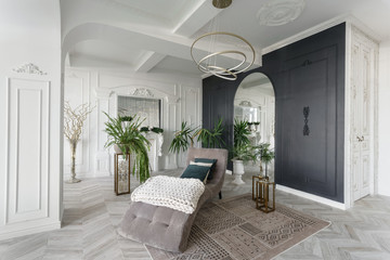 Fototapeta premium Morning in luxurious light interior in hotel. Bright and clean interior design of a luxury living room with parquet wood floors, fireplace, sofa and houseplant. Stucco on walls