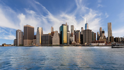 Skyline of New York with clouds in the sky and reflect in the water