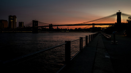 Silhouette of the Brooklyn Bridge at sunrise with reflection in the water