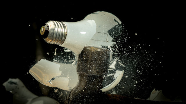 Hammer smashes an incandescent light bulb in the dark