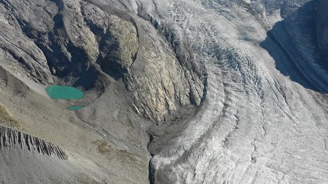 Aerial view of the Gorner glacier with its crevasses and a green pond in the evening light in Zermatt, Switzerland