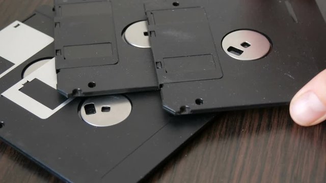 Female hand throwing old vintage diskettes or floppy disk on the table