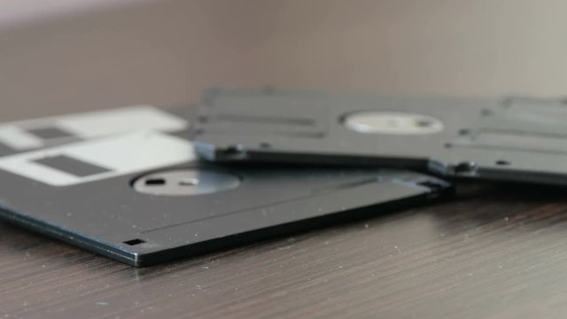 Female hand takes old vintage diskettes or floppy disk on the table