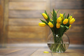 A bouquet of yellow tulips in a vase on the floor. A gift to a w