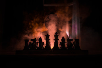 Man playing chess. Scary blurred silhouette of a person at the chessboard with chess figures. Dark toned foggy background.