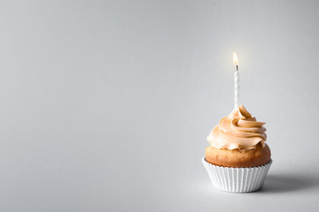 Delicious birthday cupcake with candle and space for text on gray background