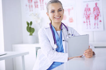 Portrait of friendly female doctor with stethoscope and tablet in hands.