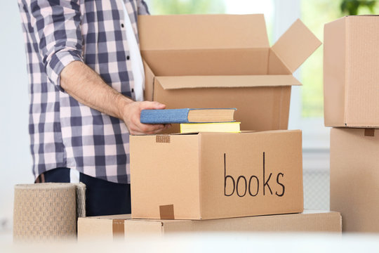 Man putting books into box indoors, closeup. Moving day