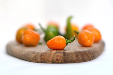Orange mini pepper on a background of orange and green peppers lying on a wooden board.