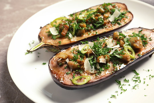 Plate with tasty stuffed eggplants on gray table