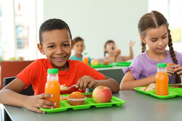Children sitting at table and eating healthy food during break at school - Powered by Adobe