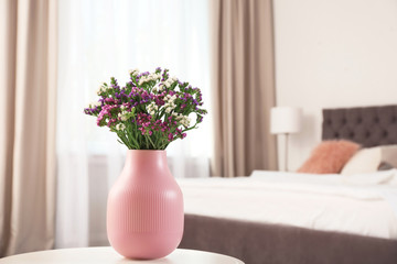 Obraz na płótnie Canvas Beautiful flowers in vase and space for text on blurred background. Element of interior design