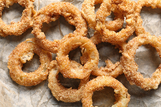 Parchment paper with homemade crunchy fried onion rings, top view