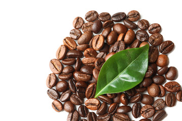 Roasted coffee beans and green leaf on white background, top view