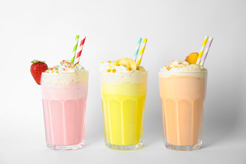 Glasses of tasty milk shakes on white background