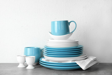 Set of dinnerware on table against light background. Interior element