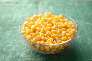 Bowl with corn kernels on green wooden background