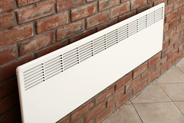 Modern heating convector on brick wall indoors