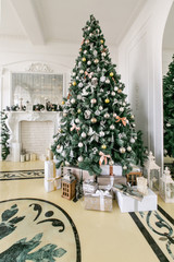 Presents and Gift boxes under Christmas Tree. Beige boxes with ribbon bow. New year decorated house interior. Winter Holiday concept.