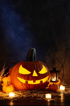 Carved pumpkin or jack-o-lantern in dark barn, Halloween holiday celebration concept