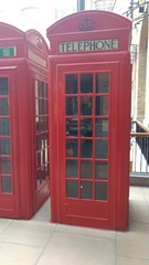 Young men in red telephone booth in london