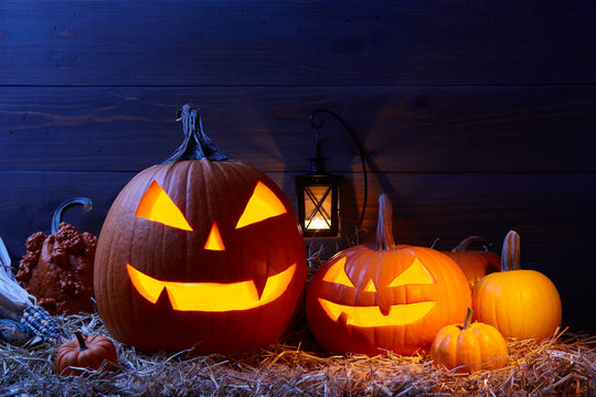 Carved pumpkins or jack-o-lanterns in dark barn, Halloween holiday celebration concept