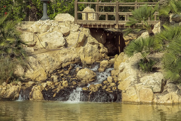 Fototapeta na wymiar little cascade and wooden bridge in El palmeral park