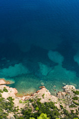 Spectacular aerial view of a beautiful wild and rocky coast bathed by a clear and turquoise sea, Sardinia, Italy.