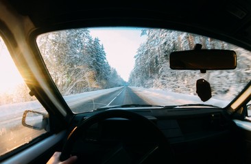 Fototapeta premium driving behind the wheel of a driver on a forest winter snowy road.