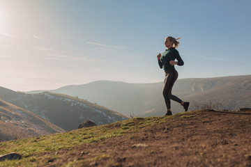 Young fit woman running on a mountain top