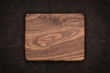 Handmade black walnut rectangular chopping board on handmade smeared burlap, walnut texture background