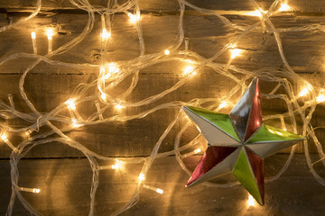 Christmas star ornament and christmas lights on vintage wooden background