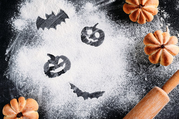 Drawing Halloween decorations on flour background, cakes in the shape of pumpkin and rolling pin....