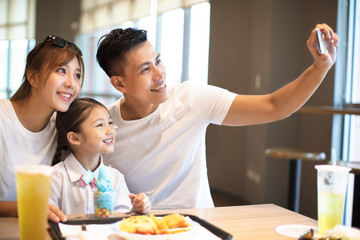 Happy family taking selfie in restaurant.
