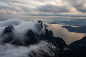Aerial view of Canadian Mountain Landscape covered in clouds during a vibrant summer sunset. Taken near Vancouver, BC, Canada.