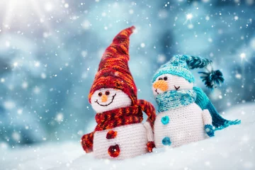 Foto op Canvas kleine gebreide sneeuwpoppen op zachte sneeuw op blauwe achtergrond © candy1812