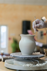 the Potter molds a pot from clay on a Potter's wheel. The master's hands make a pot on the potter's wheel. vertical photo